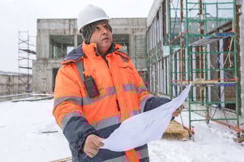 Construction manager at a job site looking over a blueprint of the project